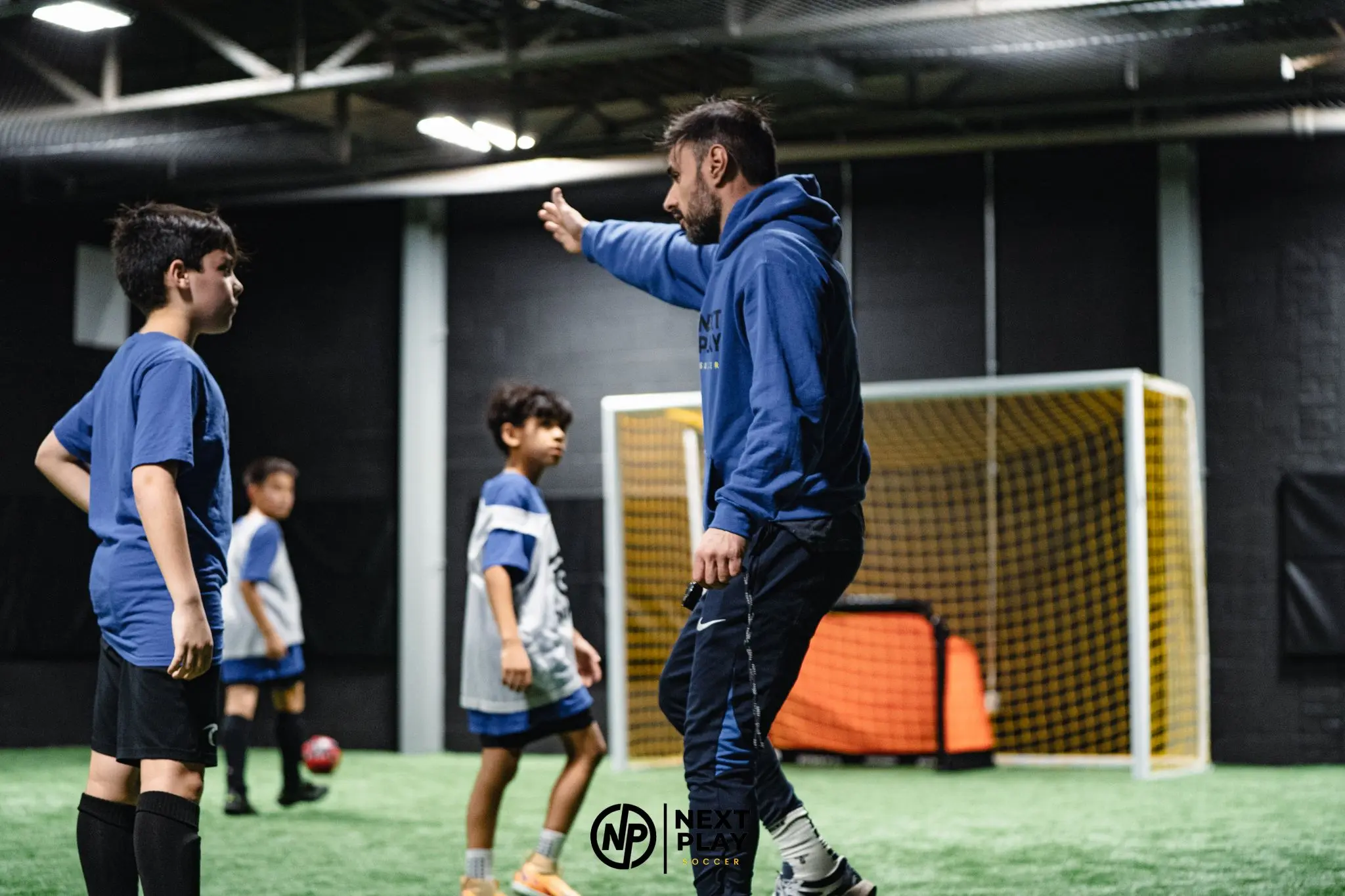 Youth soccer coach giving individual instruction during training